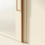 Gros plan sur une porte coulissante blanche à cadre cuivré contre un mur beige, illustrant l'espace entre la porte et le mur.